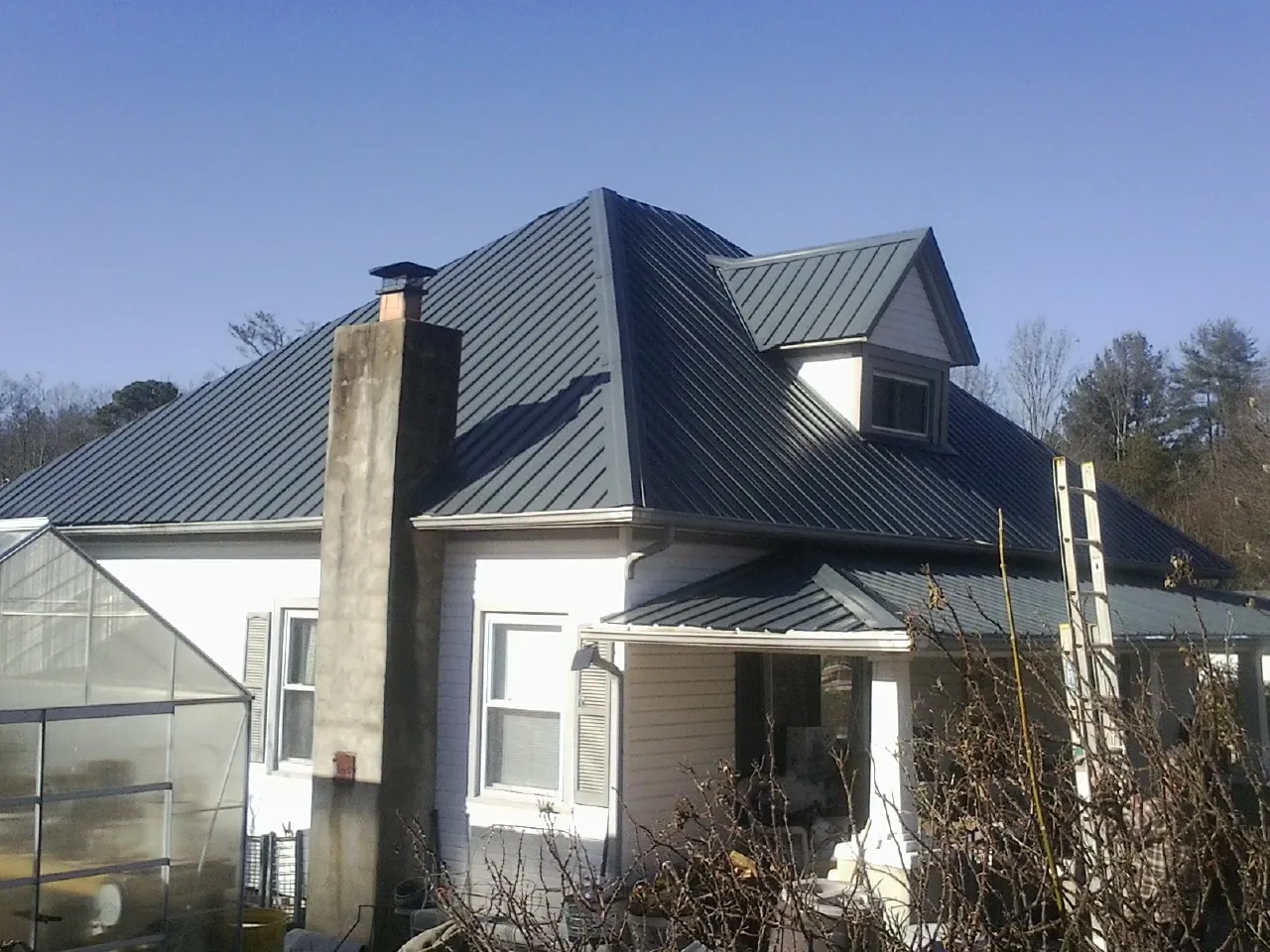 Dark blue standing seam metal roof on a white farmhouse with dormer — Slate & Tile Roof Repair by Roofing Brothers in Narberth