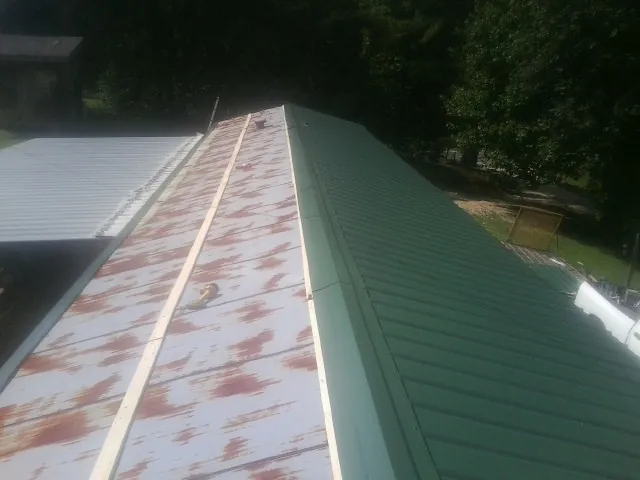 Old rusted panels beside newly installed green metal roofing — Wind Damage Roof Repair by Roofing Brothers in Narberth