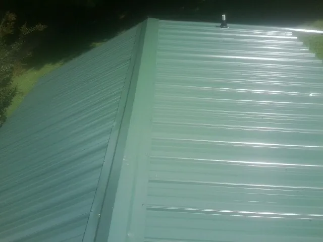 New green metal panels meeting at the ridge of a roof — Flat Roof Repair work by our crew in Narberth