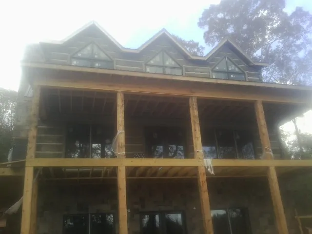 Dormers and porch framing on a large log home under construction — Roof Coating work by our crew in Narberth